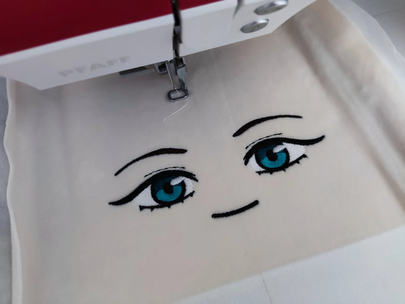 WIP embroidery close up of Uta Komagawa plush face, hoop embroidery process showing handmade anime eyes design – rostro bordado peluche Uta Komagawa proceso bordado bastidor handmade